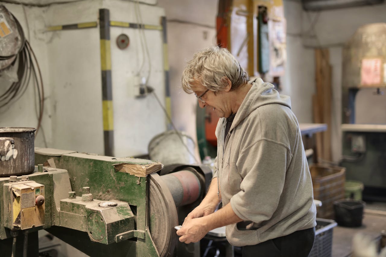 services-04 Elderly craftsman concentrating on his work in an industrial workshop.
