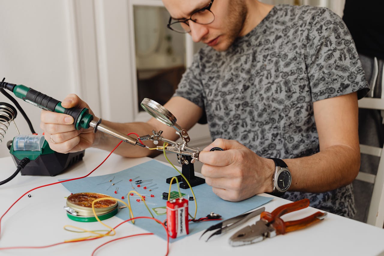 about-us-02 Adult technician soldering electronics with precision tools and equipment indoors.